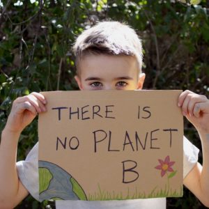 child holding "There is no planet B" sign looking at the camera